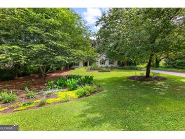 Charming home with a beautiful landscaped front yard and mature trees at 205 N Strathmore Dr, Sharpsburg, GA 30277