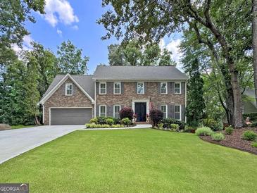 Charming brick two-story home with manicured lawn, beautiful landscaping, and a two-car garage at 335 S Satinwood Pl, Roswell, GA 30076