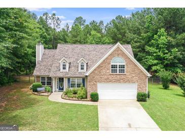 Charming two-story home featuring a stone facade, well-manicured lawn, and an attached two-car garage at 320 Cobb Ct, Hampton, GA 30228