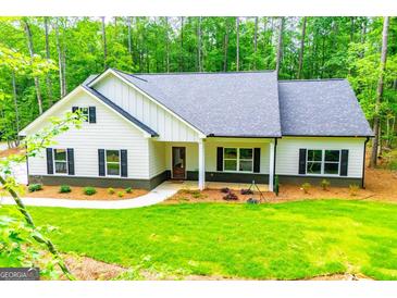 Inviting single-story home with a well-manicured lawn and charming curb appeal surrounded by a lush green forest at 5525 Belle Meade Dr, Villa Rica, GA 30180