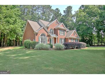 Beautiful brick home featuring a well-manicured lawn and lush landscaping at 185 Newfield Dr, Tyrone, GA 30290