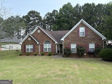 Charming brick home with well-manicured lawn, red shutters, and lush landscaping at 85 Bermuda Run Dr, Covington, GA 30016