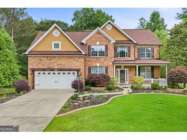 Charming two-story brick home with a well-manicured lawn, attached garage, and inviting front porch at 52 Olivia Ct, Palmetto, GA 30268