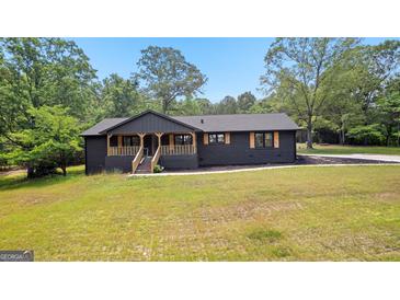 Charming black home with a covered front porch and natural wood accents surrounded by lush greenery at 8129 S Giles Rd, Douglasville, GA 30135