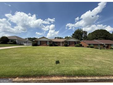 Charming brick home with manicured lawn and tidy landscaping under a partly cloudy blue sky at 410 Clubland Se Cir, Conyers, GA 30094