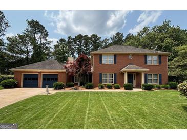 Charming brick home featuring a two-car garage, manicured lawn, and traditional design with blue shutters at 404 Windsor Way, Peachtree City, GA 30269