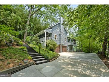 Beautiful two-story home featuring a 2-car garage, wood siding, stone chimney and stairs leading to the front porch at 610 Lake Dr, Snellville, GA 30039