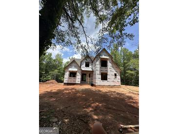 View of the home's exterior under construction surrounded by lush greenery and a partially cloudy sky at 385 Snead, Fayetteville, GA 30215