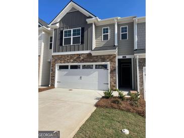 Two-story townhome featuring a stone facade, two-car garage, and neutral-toned siding at 1404 Gray Branch Dr, Lawrenceville, GA 30045