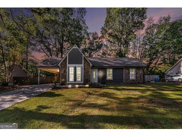 Charming home featuring stone accents, a covered carport, a well-manicured lawn, and tasteful landscaping at 113 Caldwell Dr, Hampton, GA 30228