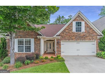 Charming stone front exterior with well-manicured lawn and attached two-car garage with bright white doors and trim at 370 Grand Teton Cir, Fayetteville, GA 30215