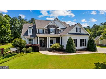 Eye-catching two-story home showcasing stone accents, dark shutters, professional landscaping, and lush green lawn at 55 Jolie Ln, Sharpsburg, GA 30277