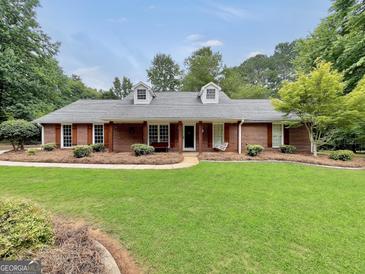 Charming brick home with a well-manicured lawn, dormer windows, and inviting front porch swing at 602 Pine Knoll Court, Mcdonough, GA 30252