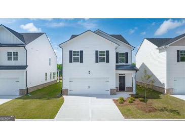Two-story home featuring white siding, black shutters, a two-car garage, and a well-manicured lawn at 11884 Aukerman Way, Hampton, GA 30228