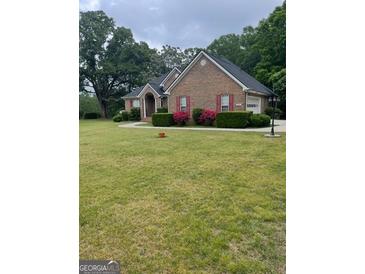 Well-maintained brick home with a spacious front yard and blooming shrubs at 2142 E Atlanta Rd, Stockbridge, GA 30281