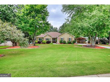 Inviting home featuring a well-manicured lawn, mature trees, and charming curb appeal at 55 Ashton Pl, Covington, GA 30016