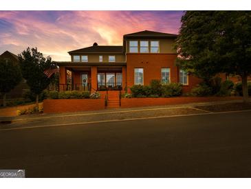 Stunning two-story brick home with manicured landscaping and an inviting front porch under a vibrant sunset sky at 185 Central Ave, Fayetteville, GA 30214