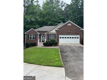 Charming single-story brick home featuring a two-car garage and well-maintained landscaping in a lush, green setting at 2074 Ayers Creek Ct, Villa Rica, GA 30180