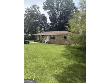 Charming brick ranch home with a lush green lawn and mature trees at 341 Boxwood St, Social Circle, GA 30025