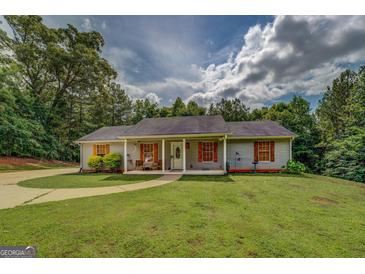 Charming single-story home features a well-manicured lawn and inviting covered front porch at 527 Malcom Rd, Covington, GA 30014