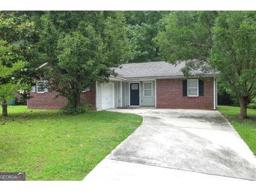 Charming brick home featuring a paved driveway, lush lawn and mature shade trees enhancing curb appeal at 2039 Faith Cv, Atlanta, GA 30349