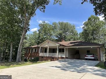 Inviting single-story home with a covered porch and a spacious carport nestled among lush trees at 370 Rosetta Nw Ln, Conyers, GA 30012