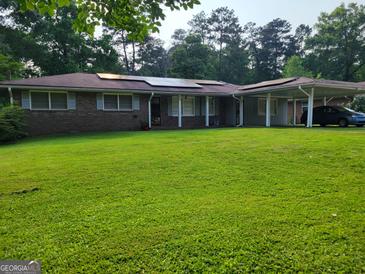 Charming brick home with a well-maintained lawn, solar panels, and a convenient carport at 4157 Cedar Valley Ln, Conley, GA 30288