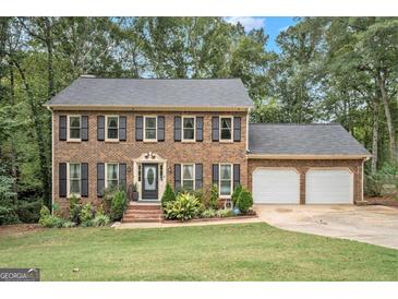 Charming brick home with a well-manicured front yard, black shutters, and a two-car garage at 1911 Geyser Trce, Lawrenceville, GA 30044