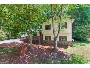 Charming two-story home with a stone foundation and a spacious deck, surrounded by lush trees at 2031 Dennis Pl, Buford, GA 30519