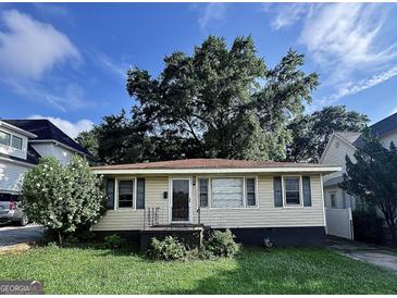 Charming single-story home featuring a cozy front porch and well-maintained lawn and a big tree at 1511 Walker Ave, Atlanta, GA 30337