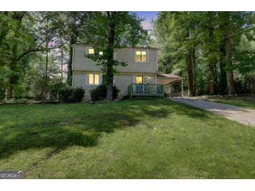 Two-story home with vinyl siding, a carport, and a well-maintained front lawn surrounded by mature trees at 405 Abbey Rd, Peachtree City, GA 30269
