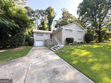 Charming brick home with a well-manicured lawn, stone accents and a red front door at 3456 Spring Cir, Decatur, GA 30032