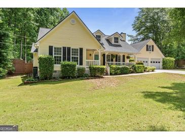 Charming yellow home featuring a lush front yard, covered porch, and an attached two car garage at 537 Country Lake Dr, Mcdonough, GA 30252