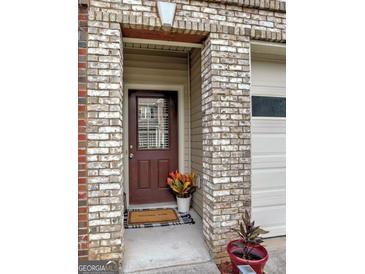 Charming front entrance with brick detail and welcoming door mat, creating an inviting entryway at 7177 Fringe Flower Dr, Austell, GA 30168