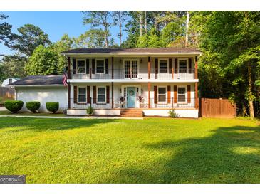 Charming two-story home with double balconies, shutters, a brick facade, and a well-manicured lawn at 103 Chipstone Ct, Peachtree City, GA 30269
