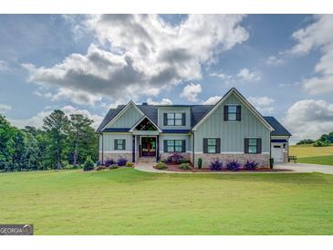 Stunning two-story home with light green siding, stone accents, and beautifully landscaped front yard at 3076 East Lake Rd, Mcdonough, GA 30252