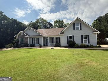Charming single-story home with gray siding, stone accents, mature landscaping, and a lush green lawn at 1422 New Holland Cir, Mcdonough, GA 30252