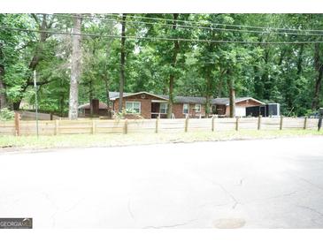 Charming single-story brick home with mature trees and a rustic wooden fence at 3010 Waters Rd Sw, Atlanta, GA 30354