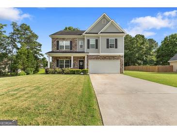 Charming two-story home featuring stone accents, a well-manicured lawn, and a spacious two-car garage at 140 Canyons, Hampton, GA 30228