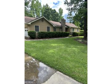 Charming single-story home features a well-manicured front yard and a classic brick chimney at 8440 Winston Way, Jonesboro, GA 30236