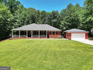 Charming red brick home featuring a welcoming front porch and lush green lawn with a detached garage at 543 Wynn Rd, Mcdonough, GA 30252