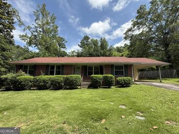 Charming brick home with a lush green lawn and a convenient covered carport at 402 Stone St, Oxford, GA 30054