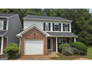 Charming two-story home featuring a brick facade, attached garage, and a well-maintained front yard with lush landscaping at 2378 Charleston Se Pt, Atlanta, GA 30316