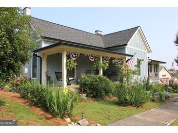 Charming home featuring a welcoming covered porch decorated with patriotic bunting and lush landscaping at 5880 Mulberry St, Austell, GA 30168