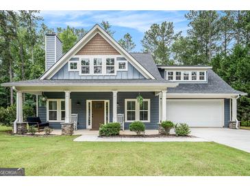 Charming home featuring a welcoming front porch with rocking chairs and well-manicured landscaping at 9148 Tarnwood Dr, Villa Rica, GA 30180