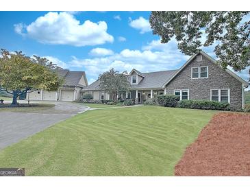Expansive front yard showing the stone and siding exterior of the home under a partly cloudy sky at 676 Mcbride Rd, Fayetteville, GA 30215