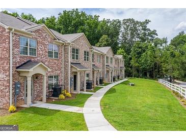 View of brick townhomes with manicured lawns and a concrete walkway leading to each unit's front entrance at 3358 Mount Zion Rd, Stockbridge, GA 30281