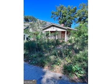 Exterior shot of a dilapidated single-story home with an overgrown yard needing significant renovation at 1225 Bridges Sw Ave, Atlanta, GA 30310