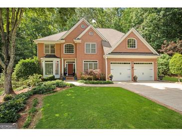 Elegant brick home featuring a well-manicured lawn and a two-car garage in a lush, green setting at 3245 Bywater Trl, Roswell, GA 30075