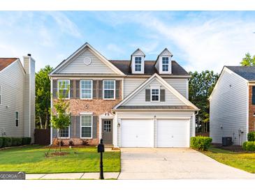 Charming two-story home featuring a brick and gray siding exterior with a two-car garage and well-manicured lawn at 8750 Redford Ln, Suwanee, GA 30024
